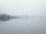 A Town Sits on the Edge of a Lake Draped in Fog