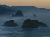 A Rocky Shoreline is Silhouetted against the Evening Sky