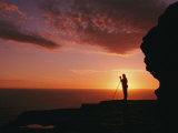 Distant View of a Silhouetted Photographer against a Brilliant Sunset