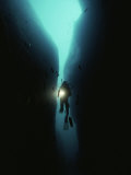 A Diver Swims Through a Large Crack in the Rock of Tgyiani Reef