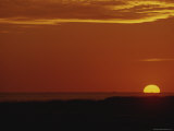 The Sun Sets Behind the Water in an Orange Sky