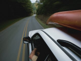 A Car with a Kayak on Top Speeds Down a Two-Lane Highway