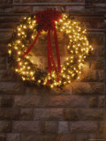 A Lighted Christmas Wreath Hangs on a Stone Building