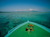 A Boat Anchored over a Reef in Clear Water  with a Mountain in Distance