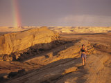 Woman Trail Running in a Rocky Landscape with a Rainbow