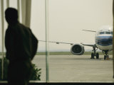 Man at a Chinese Airport Walks Past an Airplane Parked outside