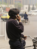 A Chinese Person Speaks on a Cell Phone While Riding a Bicycle