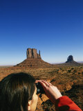 A Woman Looks Through Binoculars at the Mitten Buttes