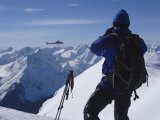 A Back-Country Skier Watches a Heli-Ski Chopper Approach a Peak