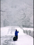 Woman Walks Along a Snowy Road with Skis and Luggage