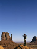 A Woman Looks Through Binoculars at the Mitten Buttes