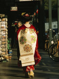 Kimono-Clad Geisha Walks Past Shops and Parked Bicycles; she is a Maiko or Apprentice Geisha