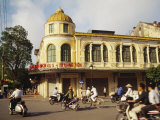 Locals Pass by an Old Colonial Building on Motorbikes in Hanoi