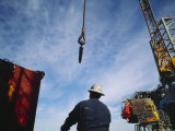 A Worker Uses a Crane and Hoist to Lift a Large Container onto an Oil Rig