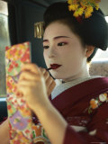 A Kimono-Clad Geisha Applies Lipstick in the Back of a Cab