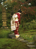 Kimono-Clad Geisha Stands on a Bridge Over a Stream in a Park