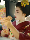 A Kimono-Clad Geisha Applies Lipstick in the Back of a Cab