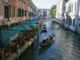 A Gondolier Passes a Restaurant on a Canal in Venice  Italy