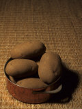 A Group of Baking Potatoes Sit in a Brass Cooking Pot