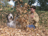 Man Playing with Dog in Autumn Leaves