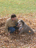 Man Playing with Dog in Autumn Leaves