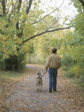 Man Walking a Dog Through Autumn Park