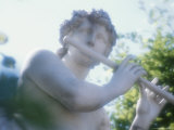 White Stone Sculpture of Woman Playing Flute Amongst Trees