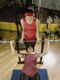Trainer Helping Young Woman Exercise with Weights