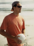 Young Man Holding a Volleyball on The Beach