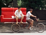 A Chinese Man Rides on a Sofa as Another Pedals a Delivery Tricycle