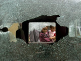 An Iraqi Woman with a Child Peers Through a Shattered Window of a Destroyed Car