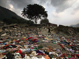 A Pakistani Refugee Walks Past Clothing Left Strewn on the Ground