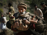 An Elderly Pakistani Earthquake Survivor Rushes Towards a Helicopter Carrying a Child in His Arms