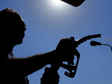 An Employee of a Petrol Station Holds a Petrol Pump after Filling up a Car
