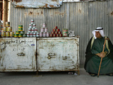 A Palestinian Sits Near the Stand of a Street Seller Displaying Goods for Sale