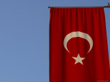 The Flag of Turkey with a White Star and Moon on Red Fabric Against Blue Sky