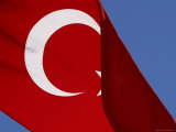 The Flag of Turkey with a White Star and Moon on Red Fabric Against Blue Sky