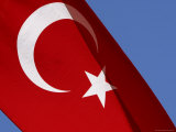 The Flag of Turkey with a White Star and Moon on Red Fabric Against Blue Sky