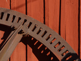 Close-up of a Rusted Round Tool Against Red Barn Siding