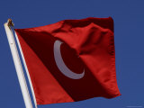 The Flag of Turkey with a White Star and Moon on Red Fabric Against Blue Sky