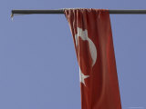 The Flag of Turkey with a White Star and Moon on Red Fabric Against Blue Sky