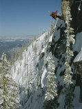 Man Rappels Down Red Mountain with a Snowboard on His Back