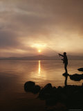 Silhouetted By the Sun  a Fly Fisherman Casts His Line Into the Lake