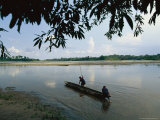 Two South American Men Launching a Canoe From a Riverbank