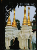 Silhouetted Monk Meditating Near Temple with Gilded Spires