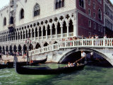 Gondolier Maneuvers His Boat Under a Bridge Crossing a Canal