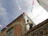 Man Preparing for Festival by Putting Up Bunting