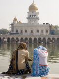 Two Women Sitting Beside Holy Water Pool at Sikh Gurdwara Bangla Sahib Temple in New Delhi