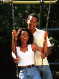 Middle-aged African-American Couple Playing on Swings in the Park