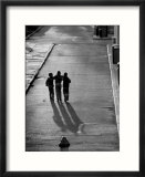 Three boys walking down street arm in arm